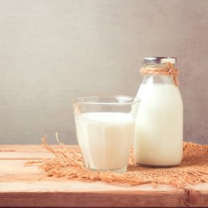Milchkanne und Milchglas auf einem Holztisch
